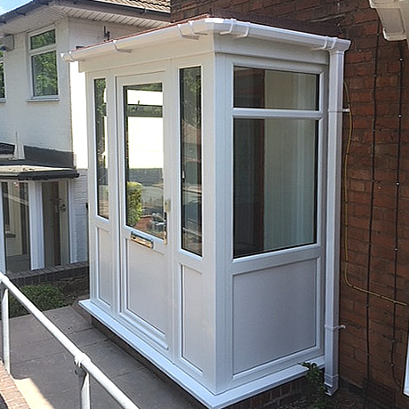 A newbuild entrance porch under construction with white profile and flat roof installed in Solihull by Solihull WDC